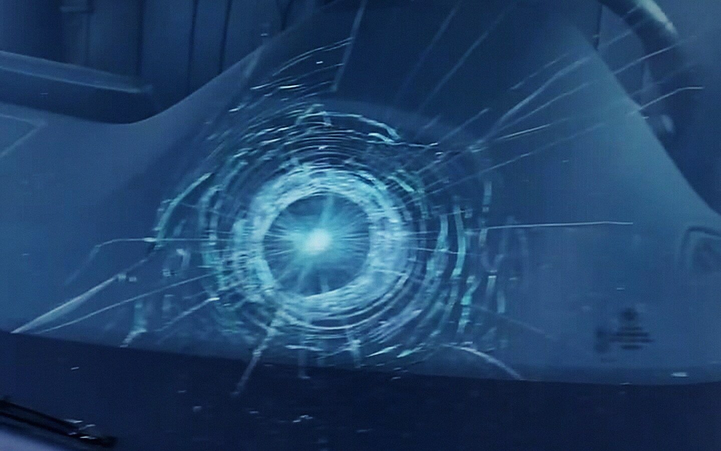 Impact star and radiating cracks in a windshield before replacement